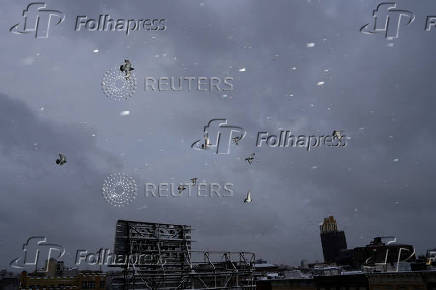 Pigeons fly during the city's first snowfall of the season, on the first day of winter in the Queens borough of New York City