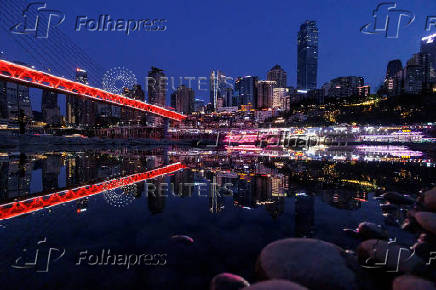 FILE PHOTO: The city skyline is reflected in a pool left on the dry riverbed of the receding Jialing river, a tributary of the Yangtze, that is approaching record-low water levels during a regional drought in Chongqing