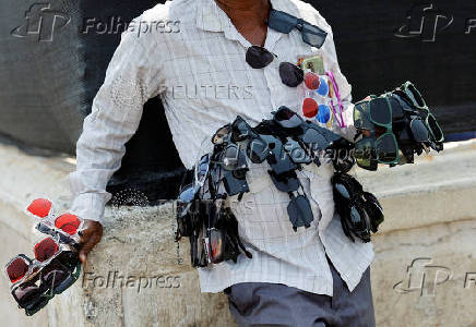 Man selling sunglasses waits for customers on a hot day in Mumbai