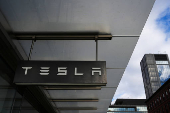 A Tesla sign hangs outside of a Tesla showroom in New York City