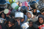 Palestinians gather to receive food cooked by a charity kitchen, in Khan Younis