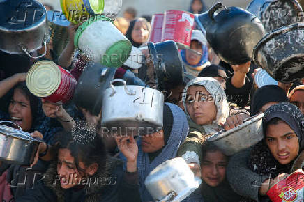 Palestinians gather to receive food cooked by a charity kitchen, in Khan Younis