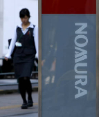 FILE PHOTO: A woman walks past a signboard of Nomura Securities outside its branch in Tokyo