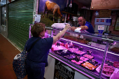 A woman shops pork meat at a market stall in Rome