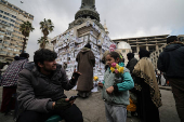 Girl sells flowers near pictures of missing people, in Damascus