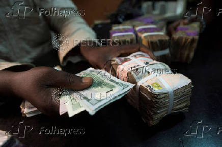 FILE PHOTO: A trader changes dollars with naira at a currency exchange store in Lagos