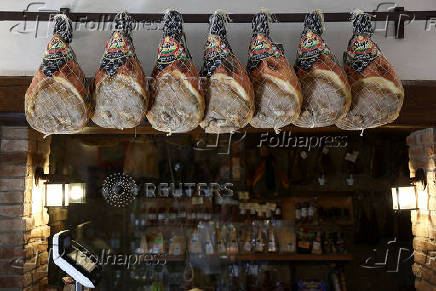 Dry-cured hams are hung at a grocery shop in Rome