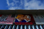 A mural depicts U.S. President Donald Trump and former U.S. President Joe Biden kissing, at the top of the Mexico-U.S. border fence at Playas Tijuana