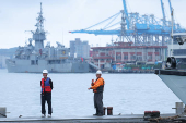 Two staff members look on as navy ships park at the port in Keelung