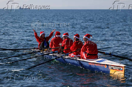 People in Santa Claus costumes row off the seafront of Thessaloniki