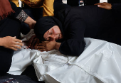 A mourner reacts next to the body of a Palestinian killed in Israeli strikes, in Rafah