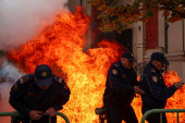 Police officers react as supporters of the opposition hurl Molotov cocktails at the mayor's office, accusing him of corruption, in Tirana