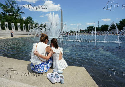 Mother and daughter dip their feet in the cool water at the World War II Memorial in Washington