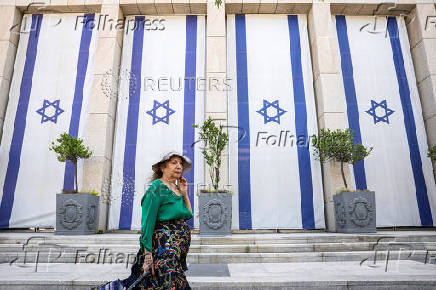 Woman walks past Israeli flags in Tel Aviv