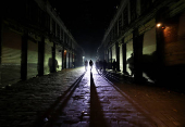 People walk next to closed shops during curfew, in Damascus