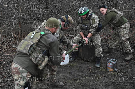 Policemen of the 'Khyzhak' Brigade clean a mortar after firing towards Russian troops at their position in a front line near the town of Toretsk