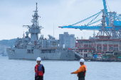 Two staff members look on as navy ships park at the port in Keelung