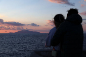 Ischia island is seen as two people hug at sunset on Capri island