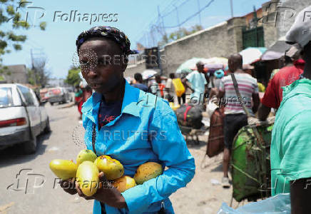 A woman carries mangoes that she bought at a market, in Port-au-Prince