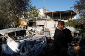 Palestinians inspect the damage at the scene, after what they said was an attack by Israeli settlers on their village of Um Safa