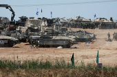 Israeli soldiers walk next to military vehicles near the Israel-Gaza border, amid the ongoing conflict between Israel and the Palestinian Islamist group Hamas, in southern Israel