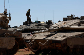 An Israeli soldier walks on military vehicles near the Israel-Gaza border, amid the ongoing conflict between Israel and the Palestinian Islamist group Hamas, in southern Israel