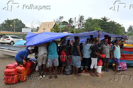 Voters and their families shelter from the rain while waiting to board small boats to vote in their provinces, in the capital Honiara