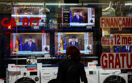 A person watches a TV broadcasting the statement by Spain's Prime Minister Sanchez, in El Masnou, north of Barcelona