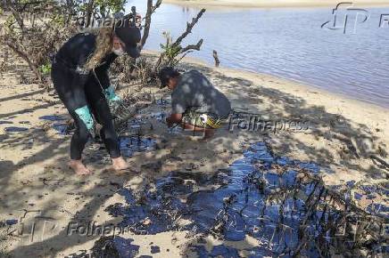 Funcionrios limpam manchas de leo na praia Boca da Barra