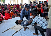 Volunteers evacuate a man playing a mock victim during a mock drill to prepare against tsunami, ahead of the 20th anniversary of the Indian Ocean tsunami, in Kaitha village