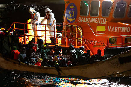 A Spanish Coast Guard vessel tows a fibreglass boat with migrants onboard to the port of Arguineguin, on the island of Gran Canaria