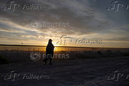 Migrant walks along bank of Rio Grande river while searching for entry into the U.S. from Mexico