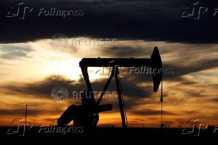 FILE PHOTO: The sun sets behind a crude oil pump jack on a drill pad in the Permian Basin in Loving County