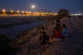 Migrants sit along the bank of the Rio Grande river in Ciudad Juarez