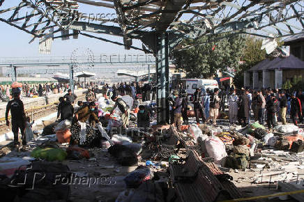 Police officers and people gather at the site amid the debris after a bomb blast at a railway station in Quetta