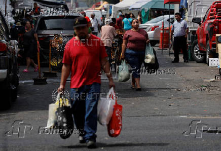 People carry shopping bags as they walk near a market in Monterrey
