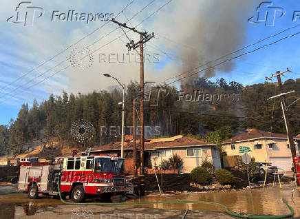 Firefighters work to stop a fire that damaged homes, in Oakland