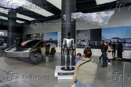 People look at a Tesla Cybertruck and a Tesla Bot at a Tesla showroom in New York City