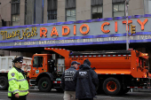 Officers from the New York City Police Department (NYPD) stand guard beside trucks from the New York City Department of Sanitation outside Radio City Music Hall