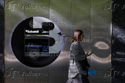 A woman walks past a branch of Spain's Sabadell bank in the Gran Via of Bilbao