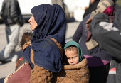 A displaced woman who fled Aleppo countryside, carries baby in Tabqa