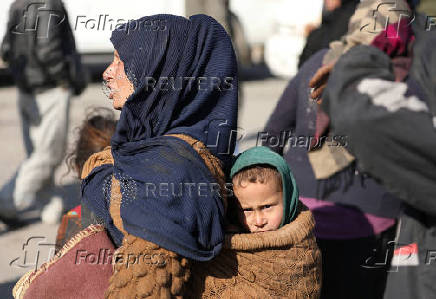 A displaced woman who fled Aleppo countryside, carries baby in Tabqa