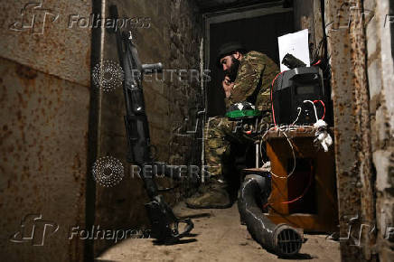 Policeman of the 'Khyzhak' Brigade sits inside a dugout at a position in a front line near the town of Toretsk