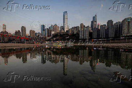 FILE PHOTO: The city skyline is reflected in a pool left on the dry riverbed of the receding Jialing river, a tributary of the Yangtze, that is approaching record-low water levels during a regional drought in Chongqing