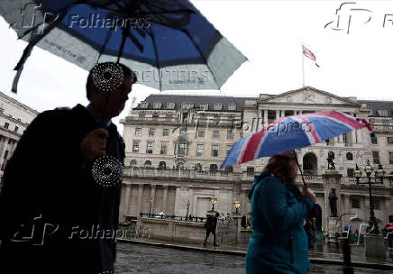FILE PHOTO: Tourists shelter from the rain under an Union Jack umbrella near the Bank of England in the City of London