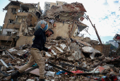 A man carries a gas cylinder as he walks on the rubble of damaged buildings in the Chiyah district of Beirut's southern suburbs