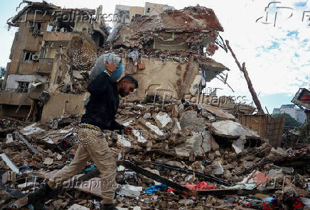 A man carries a gas cylinder as he walks on the rubble of damaged buildings in the Chiyah district of Beirut's southern suburbs