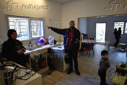 A resident of Baalbek, Abbas Wehbe, gestures as he stands with family members inside his kitchen in Baalbek