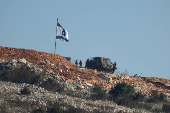 Israeli soldiers stand under an Israeli flag in southern Lebanon, near the Israel-Lebanon border