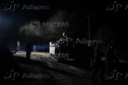 Israeli soldiers walk near a military vehicle after returning from Lebanon, following a ceasefire between Israel and Iran-backed group Hezbollah, near Kiryat Shmona